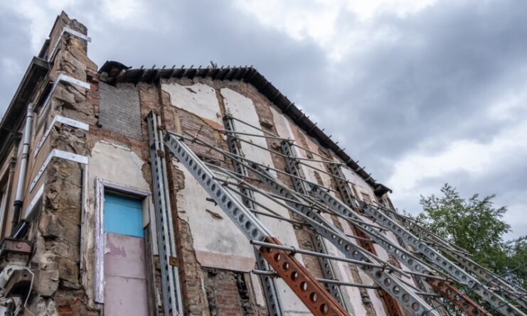 House with severe foundation damage and structural support beams installed, illustrating major structural issues homeowners may face before selling.